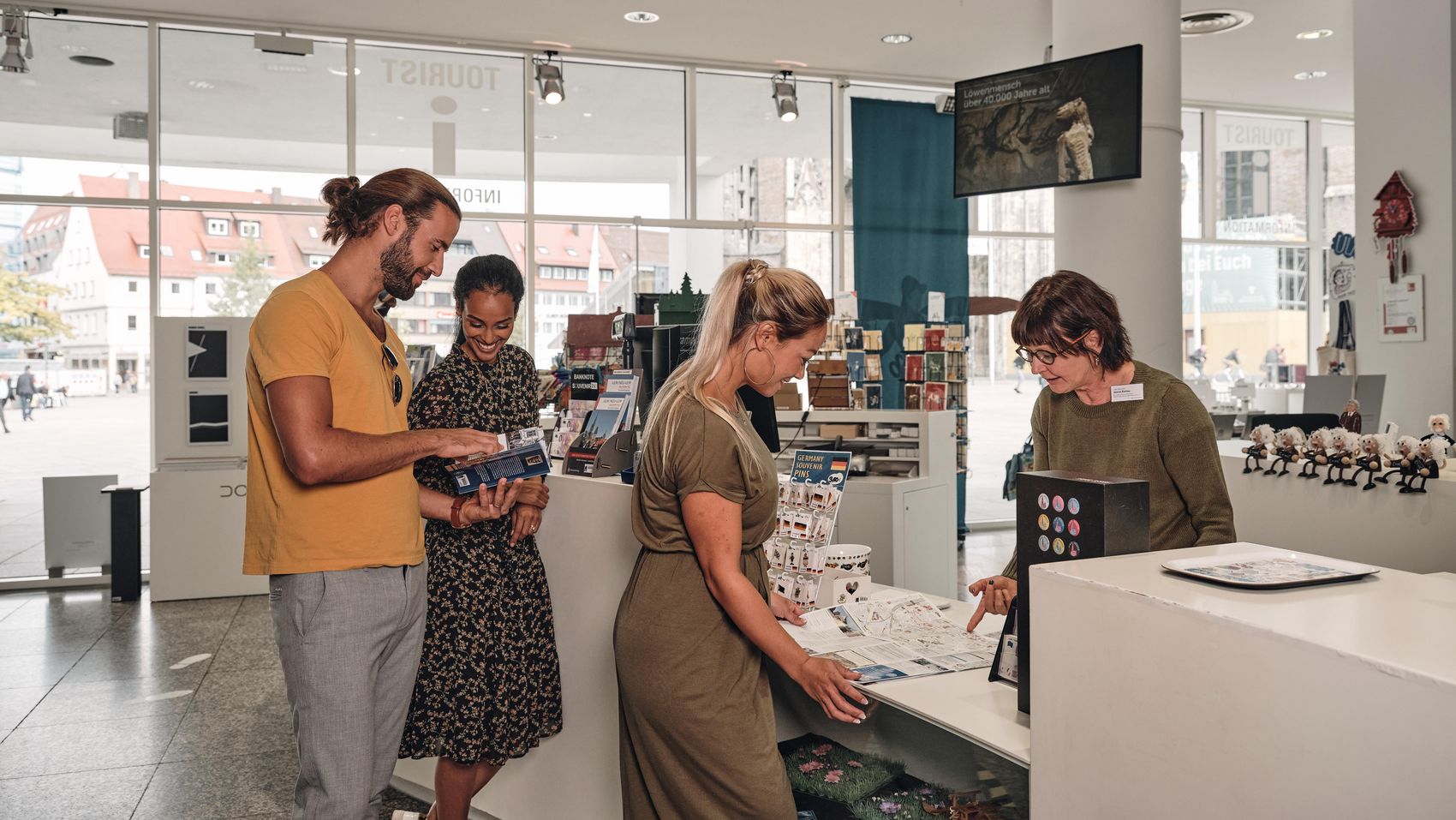 Ankommen und entdecken – erster Stopp in der Tourist-Information In der Tourist-Info beraten sich Besucher mit einer Mitarbeiterin und entdecken spannende Tipps für ihren Aufenthalt.