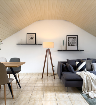 Wohnzimmer der großen Ferienwohnung: dunkelgraue Couch mit Kissen und Decken und ein Tisch mit mind. vier Stühlen | © Neckar-Zaber-Tourismus e.V.