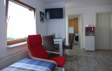 Wohn- und Schlafraum; sicht auf einen roten Sessel am Fenster und einen Schreibtisch mit zwei Stühlen | © Neckar-Zaber-Tourismus e.V.