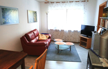 Wohnzimmer der Ferienwohnung Hipp mit rotem Sofa, Fernseher und Kamin | © Neckar-Zaber-Tourismus e. V.