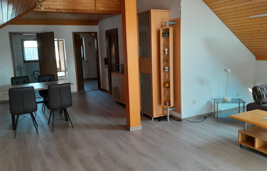 Blick in den Wohnraum der Ferienwohnung mit Esstisch und Sofa | © E. Hügler