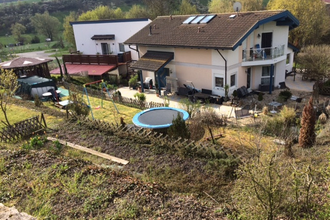 Zweistöckiges Haus mit Balkon und Terrasse, Garten mit Trampolin und Schaukel, umgeben von Bäumen und Hügeln im Hintergrund | © Jürgen Bauer