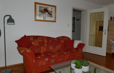 Wohnzimmer mit Blumen auf dem Tisch und bunter Couch | © Hopf