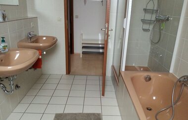 Badezimmer mit Badewanne und zwei Waschbecken und Dusche