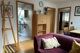 Aufenthaltsraum in der Ferienwohnung mit einer lila Couch, einem Esstisch sowie einem kleinen Schrank. | © Neckar-Zaber-Tourismus e.V.