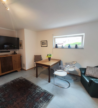 Zimmer mit Sofa, Esstisch, Stühlen und Kommode | © Lutz