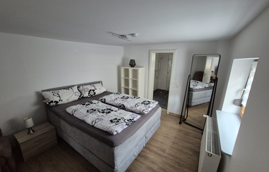 Schlafzimmer mit Holzboden, Standspiegel und Boxspringbett | © Wolf