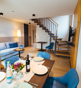 Esstisch mit mindestens 4 Stühlen, eine pastellblaue Couch, Tisch und Stuhl neben der Treppe nach oben | © Neckar-Zaber-Tourismus e.V.