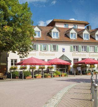 Frontansicht des Hotels vom Marktplatz aus. Vor dem Hotel sind Sonnenschirme aufgestellt. | © Flair Hotel Weinstube Lochner