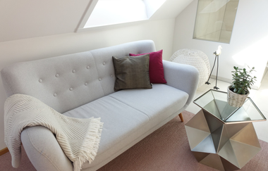 Sitzecke mit weißer Couch, rot und grauem Kissen und eine weiße Decke. Davor steht ein kleiner Tisch mit Topfpflanze. | © Neckar-Zaber-Tourismus e.V.