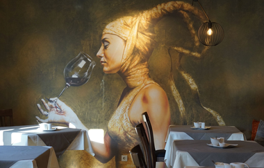 Vergrößerte Aufnahme des Hintergrundbildes im Frühstücksraum. Zu sehen ist eine Frau in gold mit hörnerähnlicher Kopfbedeckung, die ein Glas Wein in der Hand hält. | © Neckar Zaber Tourismus e.V.