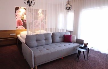 Aufnahme des Doppelzimmers. Eine große graue Couch und zwei kleine Tische. Große Fensterwand. | © Neckar-Zaber-Tourismus e.V.