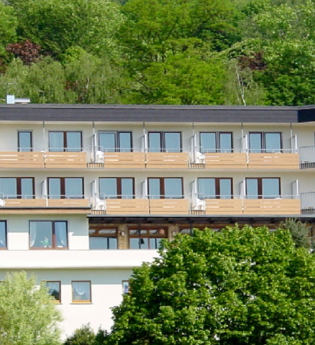 Mehrstöckiges Hotel mit Balkonen, umgeben von grünen Bäumen und bewaldetem Hang im Hintergrund | © Hotel Kippes