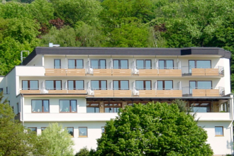 Mehrstöckiges Hotel mit Balkonen, umgeben von grünen Bäumen und bewaldetem Hang im Hintergrund | © Hotel Kippes