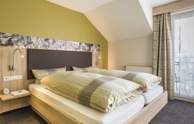 Doppelbett mit Nachttisch, belichtet | © Landpension Kohler