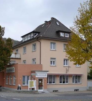 Eckgebäude mit einem Restaurant im Erdgeschoss, beige Fassade, dunkles Dach und mehreren Fenstern, umgeben von Bäumen und an einer Straße | © Stadthotel miya