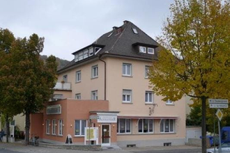 Eckgebäude mit einem Restaurant im Erdgeschoss, beige Fassade, dunkles Dach und mehreren Fenstern, umgeben von Bäumen und an einer Straße | © Stadthotel miya
