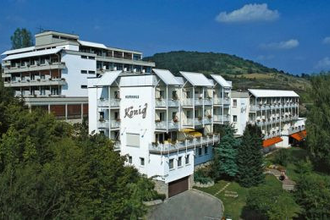 Außenansicht des Vitalhotels König, ein mehrstöckiges weißes Hotelgebäude umgeben von Bäumen und Hügeln unter blauem Himmel | © Vitalhotel König