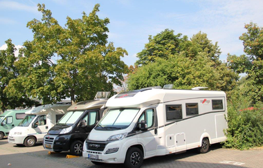 Blick auf den Wohnmobilstellplatz in Tauberbischofsheim. Einige Wohnmobile stehen neben Büschen und Bäumen. | © Stadt Tauberbischofsheim