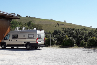 Wohnmobil auf einem Schotterplatz bei gutem Wetter mit Weinbergen im Hintergrund | © Unbekannt