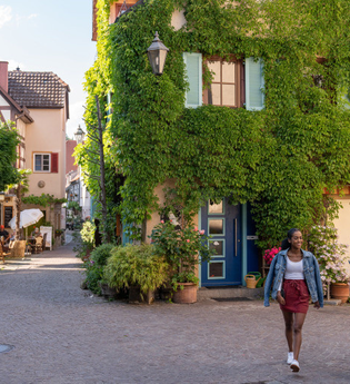 Zwei Frauen spazieren durch eine malerische Altstadt mit Fachwerkhäusern und begrünten Fassaden. | © Stadt Besigheim