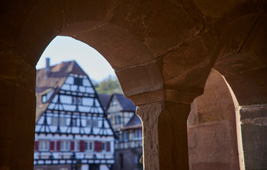 Fachwerkgebäude im Klosterhof Maulbronn durch einen steinernen Fensterbogen betrachtet | © Kraichgau-Stromberg Tourismus e.V. | Christian Ernst