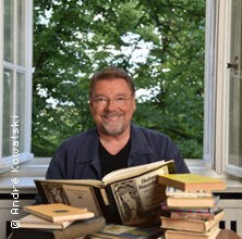 Ein Mann sitzt vor einem offenen Fenster mit Büchern auf dem Tisch. | © links im Bild