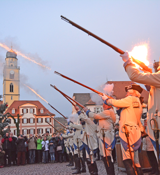 Die Historische Deutschorden Compagnie schießt auf dem Marktplatz mit ihren Gewähren in die Luft. Zuschauer schauen begeistert zu. | © Michael Weber-Schwarz