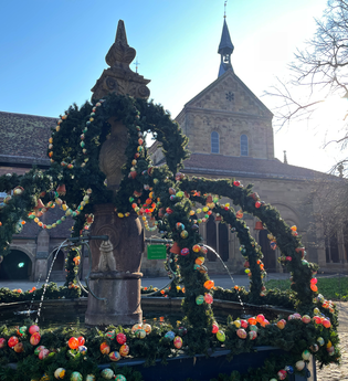 Geschmückter Osterbrunnen im Klosterhof im Hintergrund die Klosterkirche bei Sonnenschein | © Stadt Maulbronn