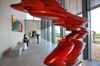 Zwei Besucher bewundern eine rote Skulptur und genießen den Ausblick ins Grüne | © Touristikgemeinschaft Hohenlohe e. V. | Firma Würth