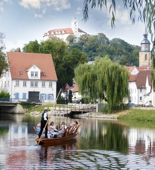 Ein Stocherkahn mit mehreren Personen fährt auf einem Fluss, im Hintergrund sind Gebäude und ein Turm zu sehen. | © Stadtverwaltung Vaihingen an der Enz