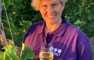 Nicole Betz mit lila Shirt der WeinErlebnisFührer und Weinglas in der Hand zwischen Weinreben | © Nicole Betz