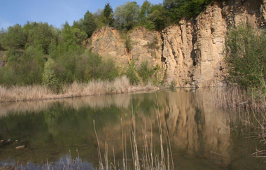 Kleiner Natursee mit bewachsenem Berg aus Steinformationen