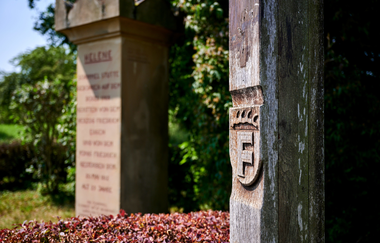 Detailaufnahme eines Holzpfostens mit geschnitztem Wappen und dahinterliegendem Gedenkstein in Freudental. | © Kraichgau-Stromberg Tourismus e.V.