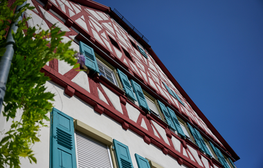 Ein prächtiges Fachwerkhaus mit roten Balken und türkisfarbenen Fensterläden vor strahlend blauem Himmel. | © Kraichgau-Stromberg Tourismus e.V.