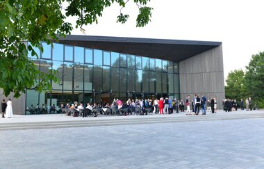 Blick auf die Tauberphilharmonie in Weikersheim. Im Eingangsbereich sitzen und stehen viele Menschen. | © Tourist-Info Weikersheim