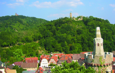 Zwei bewaldete Berge mit jeweils einer Burg auf der Spitze, im Vordergrund ist der Rote Turm und Teile der Altstadt zu sehen. | © Maria Zimmermann