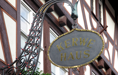 Ein altes schmiedeisernes Schild mit Schriftzug Kerwehaus an einer Fachwerkfassade. | © Maria Zimmermann