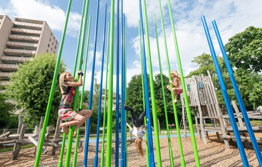 Mehrere Kinder klettern an bunten Stangen