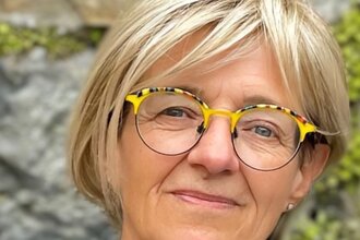 lächenlnde Frau mit blonden Haaren und Brille vor einen begrünten Mauer | © Anja Schué