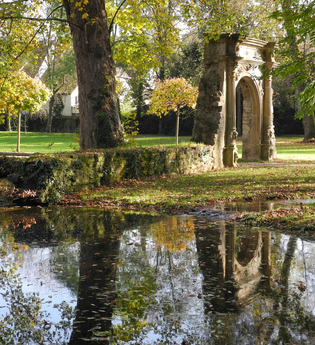 Alter Steinbogen im Park an einem Teich im Herbst
