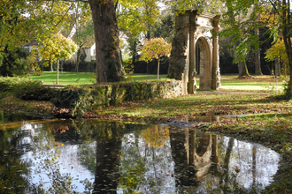 Alter Steinbogen im Park an einem Teich im Herbst
