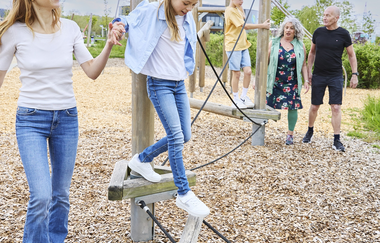 Menschen verschiedenen Alters auf hölzernen Klettergeräten im Außenbereich der Klima Arena