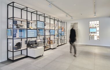 Eine Person bewegt sich auf Vitrinen mit Ausstellungsgegenständen zu | © Touristikgemeinschaft Hohenlohe e. V. | Kocherwerk Haus der Verbindungstechnik