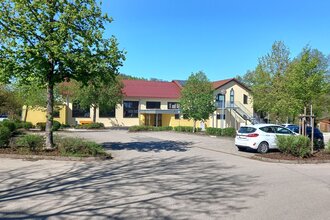 Parkplatz an der gelb gestrichenen Gemeindehalle in Ottendorf mit geparkten Autos und Bäumen im Frühling | © Petra Natzkowski