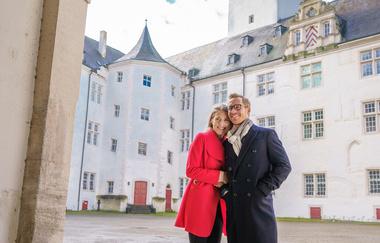 Ein Pärchen steht im Torbogen zum Schlossinnenhof. Im Hintergrund sieht man den Turm des Schlosses. | © Björn Hänssler