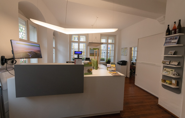 Beleuchtete Empfangstheke der Touristinfo mit Schreibtischen und Schränken