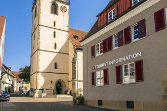 Tourist-Information neben einer Kirche mit Turm und roten Fensterläden. | © Stuttgart-Marketing GmbH, Sarah Schmid