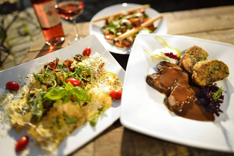 Drei ansprechend angerichtete Teller mit regionalen Spezialitäten und ein Glas Roséwein auf einem Holztisch. | © Kraichgau-Stromberg Tourismus e.V.