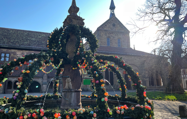 Geschmückter Osterbrunnen im Klosterhof im Hintergrund die Klosterkirche bei Sonnenschein | © Stadt Maulbronn